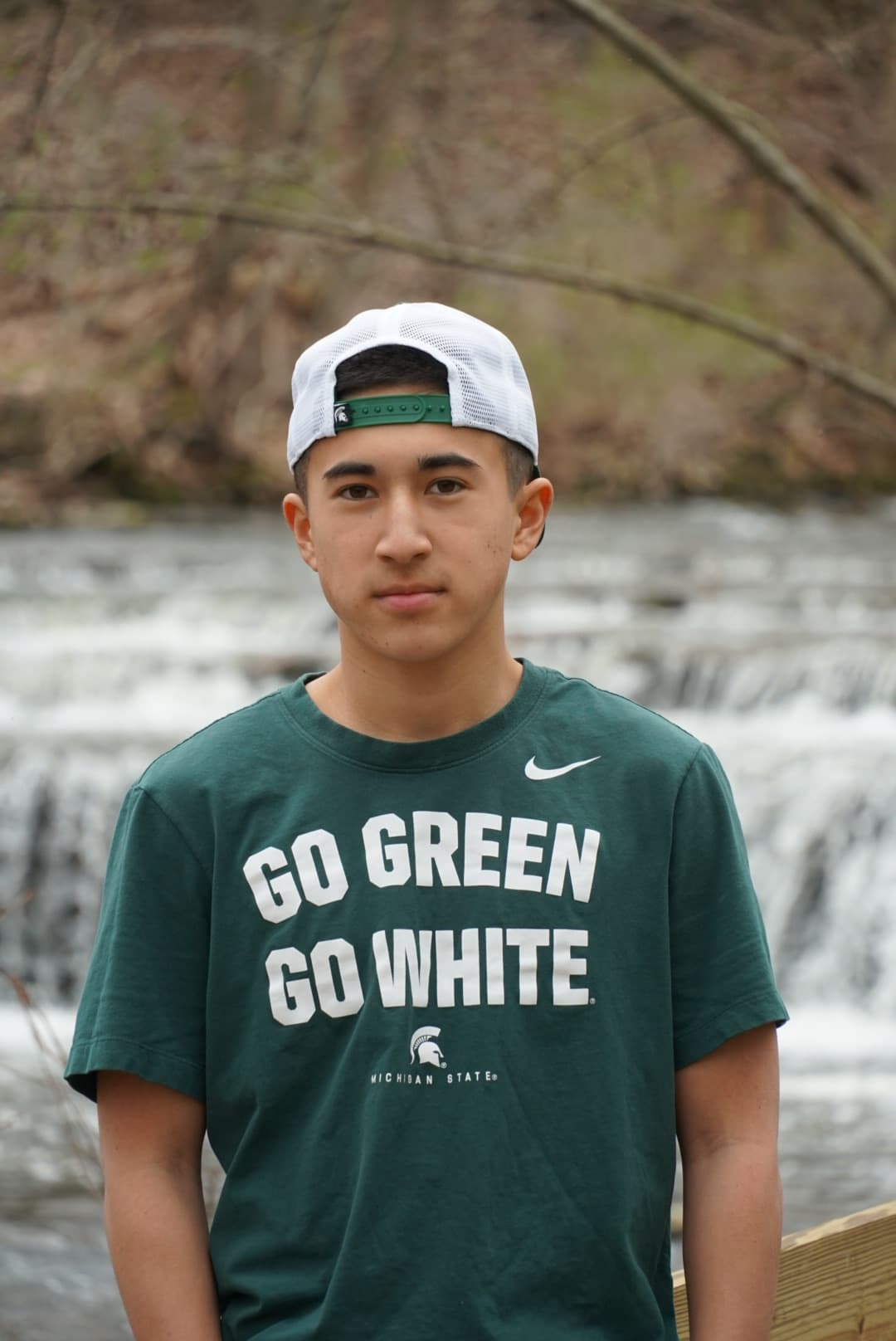 College acceptance portrait of a student in a Michigan State Go Green Go White shirt in front of a waterfall